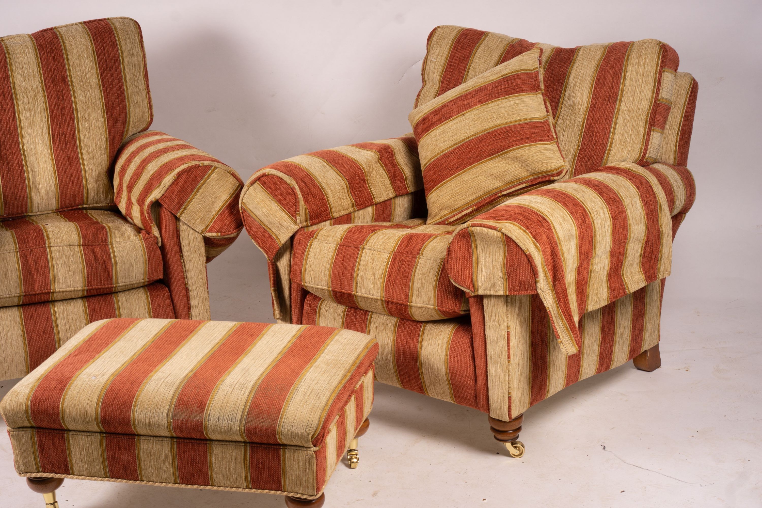 A pair of Duresta armchairs, width 94cm, depth 90cm, height 90cm and matching footstool in striped red and gold fabric